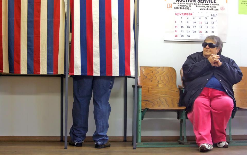 Jo Ann Banfield, of Cuba City, Wisc., waits as her son Ryan casts a vote on her behalf at the townhall in Georgetown, Wisc., on Nov. 2, 2010. Banfield is blind and is allowed to have someone vote on her behalf, according to poll workers.