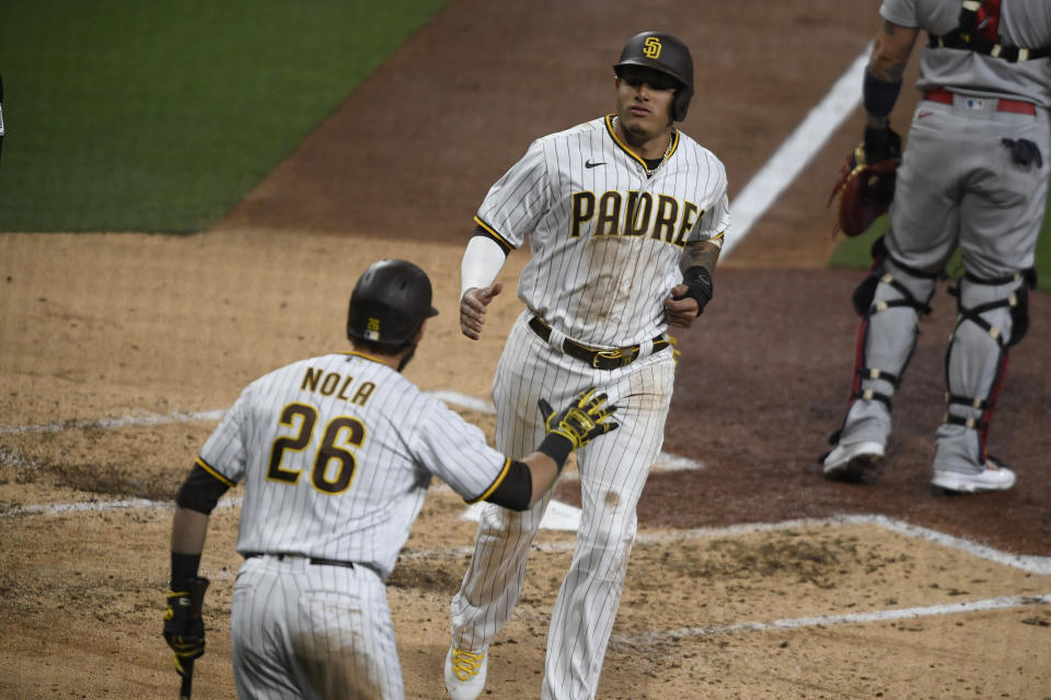 San Diego Padres' Manny Machado (13) is congratulated by Austin Nola (26) as he scores during the third inning of a baseball game against the St. Louis Cardinals, Friday, May 14, 2021, in San Diego. (AP Photo/Denis Poroy)