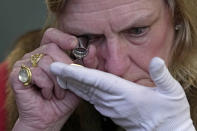 A coin is assessed during the "Trial of the Pyx,'' a ceremony that dates to the 12th Century in which coins are weighed in order to make certain they are up to standard, at the Goldsmiths' Hall in London, Tuesday, Feb. 7, 2023. A jury sat solemnly in a gilded hall in central London on Tuesday, presided over by a bewigged representative of the crown in flowing black robes, but there were no criminals in the dock. (AP Photo/Kin Cheung)