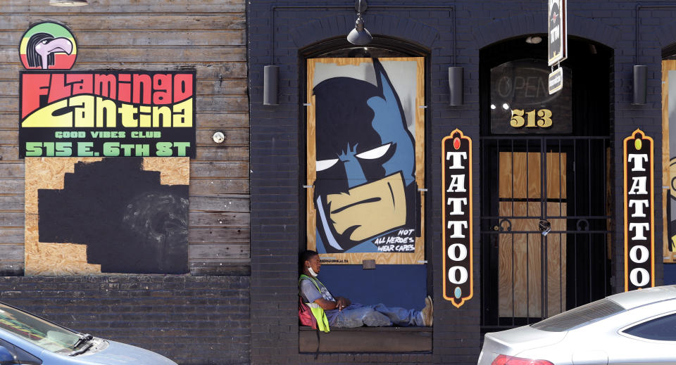 A worker sits in front of businesses that remain boarded and closed in Austin, Texas, Monday, May 18, 2020. Texas continues to go through phases as the state reopens after closing many non-essential businesses to help battle the spread of COVID-19. (AP Photo/Eric Gay)