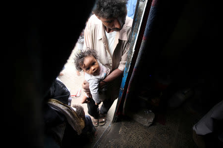 FILE PHOTO: A displaced man from Yemen's Red Sea port city of Hodeida holds his son as he stands at the door of a shelter in Sanaa, Yemen May 12, 2019. REUTERS/Khaled Abdullah/File Photo