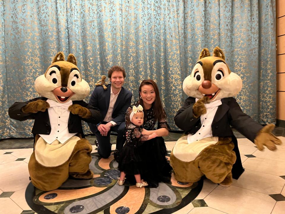 Tiffany Leigh posing for a photo with two chipmunk mascots and her husband and baby on a Disney cruise.