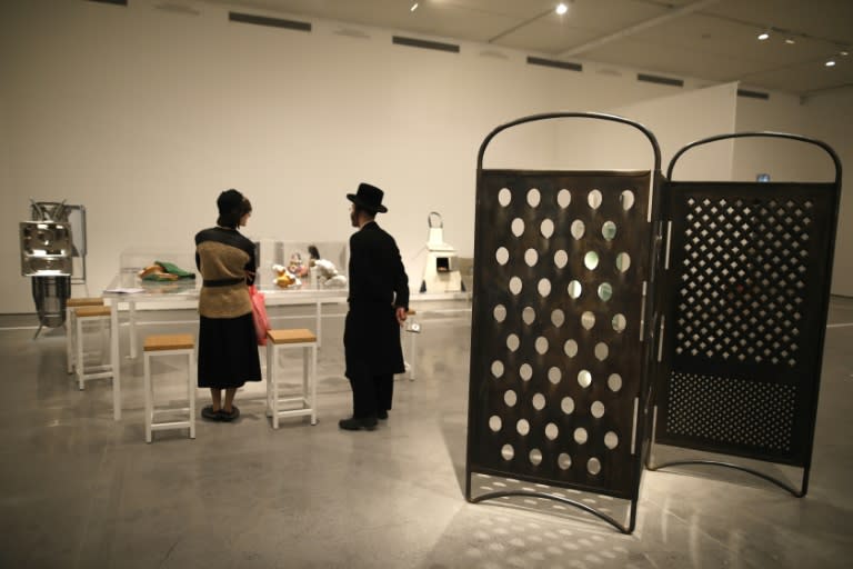 An ultra-Orthodox Jewish couple looks at an installation next to the "Grater Divide" installation (R) by artist Mona Hatoum, at the No Place Like Home exhibition in the Israel Museum in Jerusalem on February 26, 2017