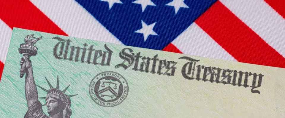 United States Treasury check and American flag. Concept of stimulus payment, tax refund and federal government grants, loans, benefits and assistance