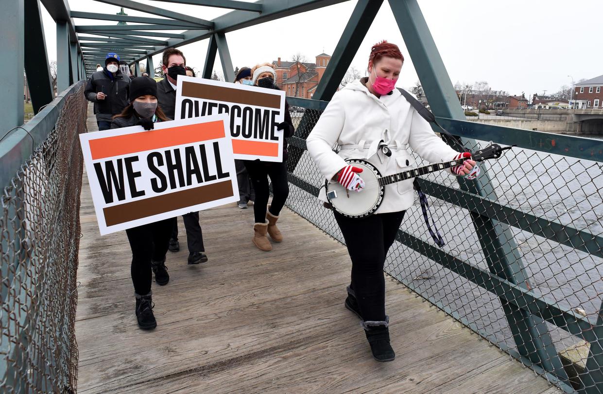 Donna Hwang of Monroe plays the banjo Jan. 19, 2021, as she leads the Monroe County Community College Unity Peace March in honor of the Rev. Martin Luther King Jr. Erika Hunt, human resources assistant at MCCC, holds the "We Shall" sign while Scott Behrens, vice president of enrollment management and student success, and Bonnie Weber of Dundee hold the "Overcome" sign as the group crosses the Martin Luther King Jr. pedestrian bridge. The 2023 Unity Peace March will take place from noon to 1 p.m. Tuesday, Jan. 17.