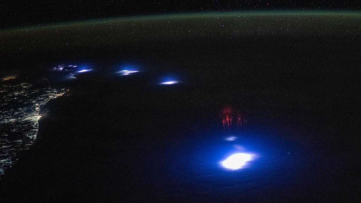  A series of lightning strikes glowing on earth beside land, illuminated with lights. 