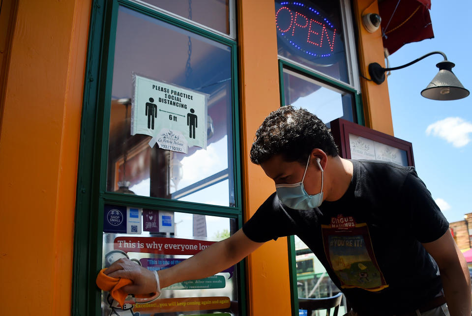 An employee wearing gloves and a face mask cleans up a restaurant in the Crystal City neighborhood of Arlington, Virginia, as restaurants and businesses try to adapt to the ever-changing situation amid the coronavirus pandemic, on May 13, 2020. (Photo by Olivier DOULIERY / AFP) (Photo by OLIVIER DOULIERY/AFP via Getty Images)