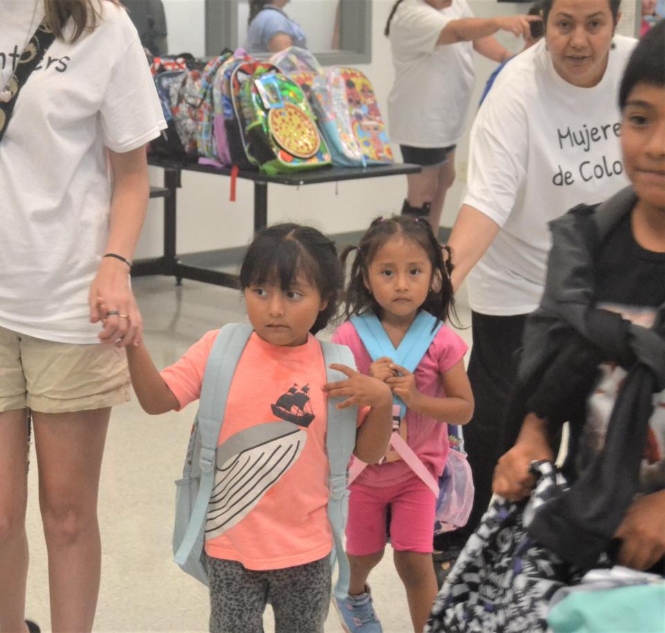 Volunteers help two young girls check out after picking out new backpacks filled with school supplies at Mujeres de Colores' annual distribution event Tuesday  at the city of Fort Collins Streets Department operations center, 625 Ninth St.