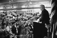 FILE - In this Wednesday, Oct. 14, 1984, file photo, a sign-waving crowd cheers Democratic presidential candidate Walter Mondale, right, as he delivers a campaign address at Victory Hall in the Milwaukee suburb of Cudahy, Wis. Campaign workers estimated 1,500 people packed the hall with another 1,000 outside. Mondale, a liberal icon who lost the most lopsided presidential election after bluntly telling voters to expect a tax increase if he won, died Monday, April 19, 2021. He was 93. (AP Photo/John Duricka, File)