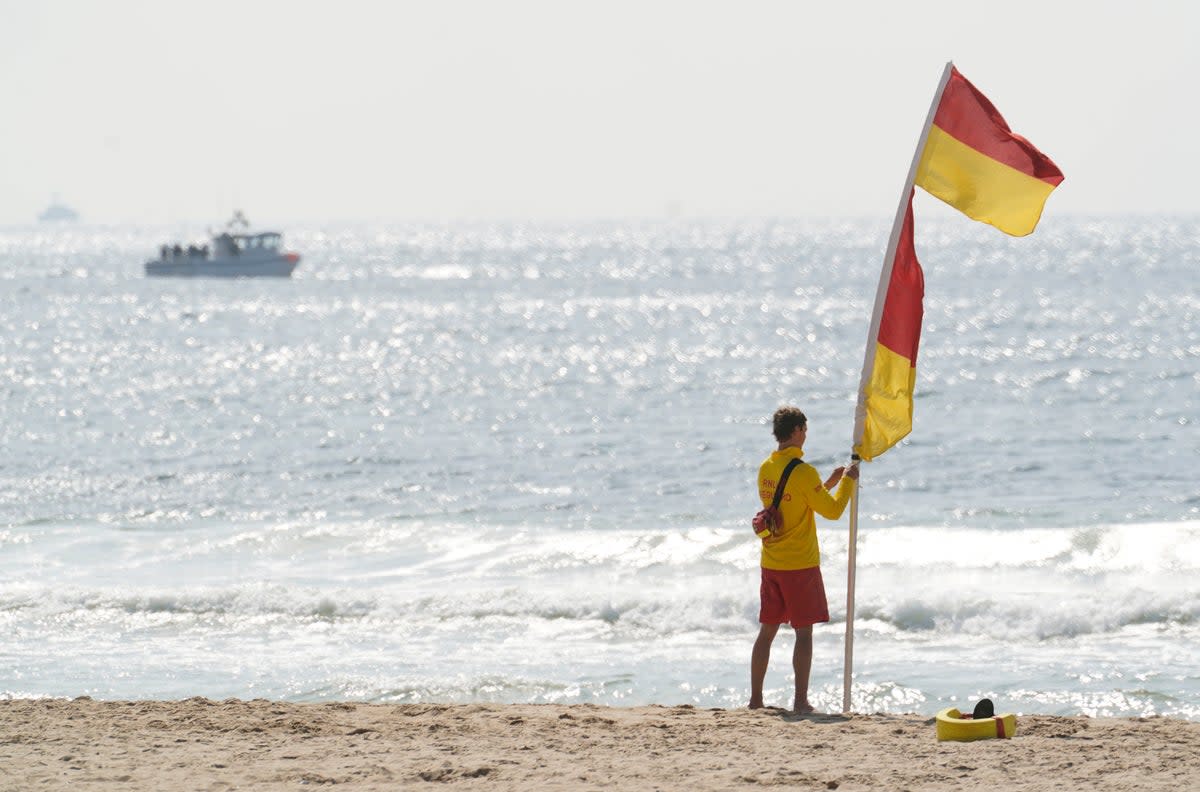 A lifeguard raises a supervised swimming flag on Bournemouth Beach a day after tragedy (PA)