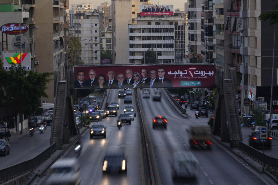 In this photo taken with slow shutter speed, cars pass under campaign posters for candidates in the upcoming parliamentary elections, in Beirut, Lebanon, Monday, May 9, 2022. Given Lebanon's devastating economic meltdown, Sunday's parliament election is seen as an opportunity to punish the current crop of politicians that have driven the country to the ground. Yet a sense of widespread apathy and cynicism prevails, with many saying it is futile to expect change. (AP Photo/Hassan Ammar)