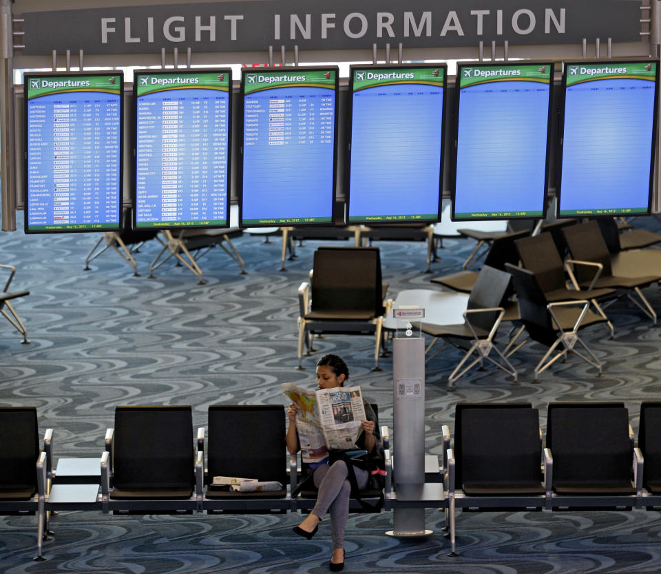 A traveler reads a newspaper under screens displaying flight information at the new Maynard Holbrook Jackson Jr. International Terminal at Atlanta's airport on the first day it begins operating flights Wednesday, May 16, 2012, in Atlanta. (AP Photo/David Goldman)