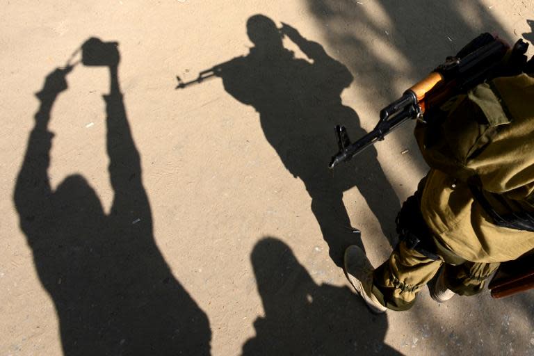 A photographer takes a picture of an armed man in military fatigues standing guard outside a regional building that was seized by pro-Russian activists in the eastern Ukrainian city of Slavyansk, on April 23, 2014