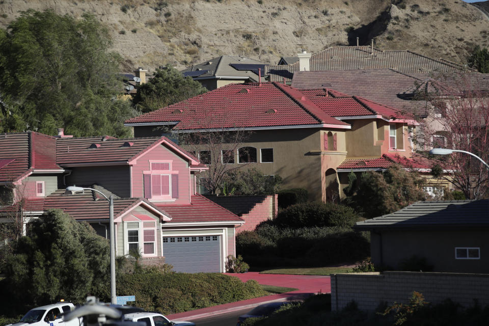 Homes are covered in fire retardant as a wildfire threatens a residential district Friday, Oct. 25, 2019, in Santa Clarita, Calif. (AP Photo/Marcio Jose Sanchez)
