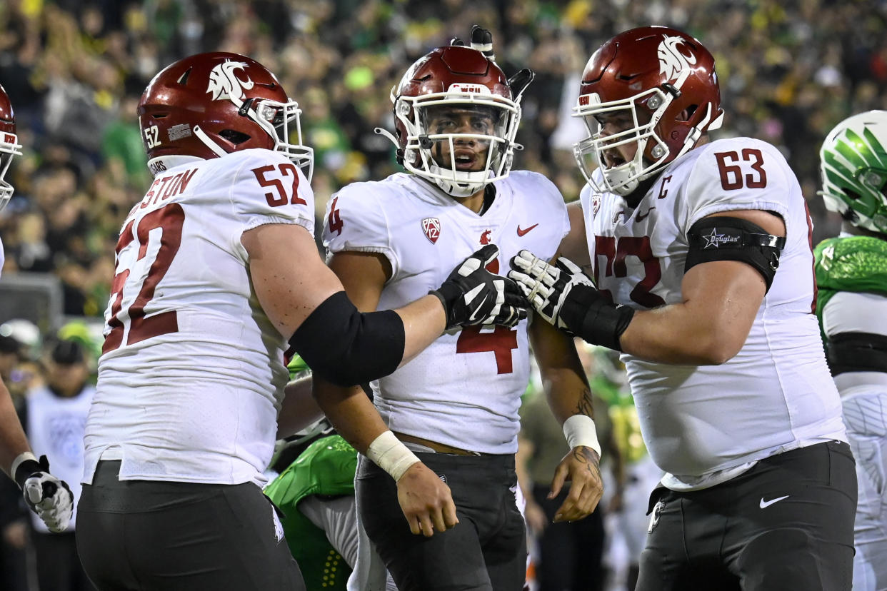 Washington State quarterback Jayden de Laura (4) celebrates his touchdown with offensive lineman Jarrett Kingston (52) and offensive lineman Liam Ryan (63) during the second quarter of an NCAA college football game Saturday, Nov. 13, 2021, in Eugene, Ore. (AP Photo/Andy Nelson)