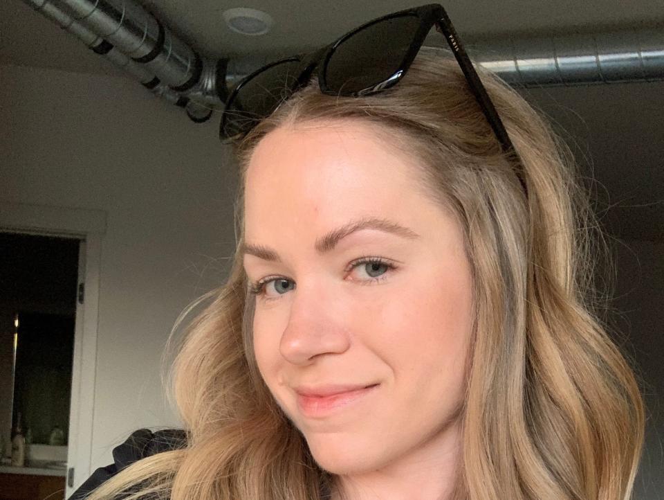 Image of Melissa Persling, who has blue eyes and long wavy blonde hair. She turns her head to the viewer's left but looks at the camera, smiling slightly. She has a mole in the right corner of her lips and wears a long-sleeve black shirt and black sunglasses on her head.