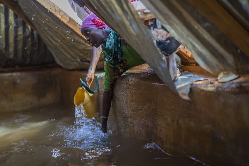 Una mujer somalí llena un recipiente con agua en un campo de desplazados a las afueras de Dollow, Somalia, septiembre de 2022.