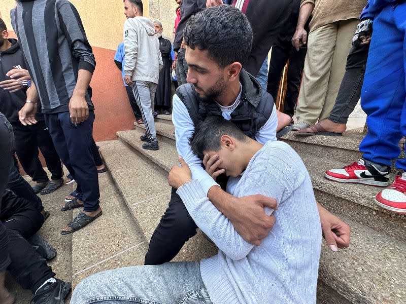 People mourn next to the body of a Palestinian killed in Israel strikes, at Nasser hospital in Khan Younis