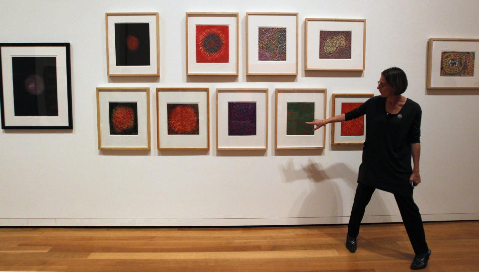 In this photo taken Tuesday, Oct. 9, 2012, a museum curator explains art by Gouache on paper by Yayoi Kasama (Flower QQ2, 1954), part of one of two new exhibits featuring art exclusively by women at the Seattle Art Museum, in Seattle. Included in the exhibition is the only U.S. stop for an exhibit from the Pompidou Center in Paris, home of the modern art museum there, of painting, sculpture, drawing, photography and video. The exhibit runs through Jan. 13, 2013. (AP Photo/Elaine Thompson)