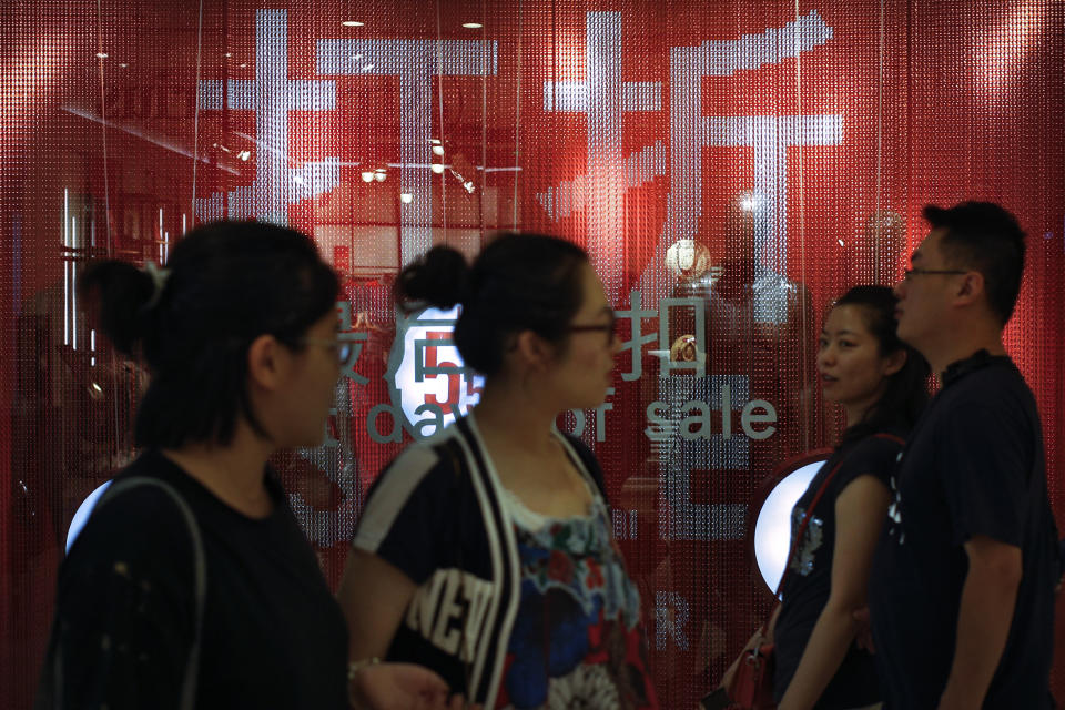 People walk by a fashion retailer having promotion sale at a shopping mall in Beijing, Monday, July 15, 2019. China's economic growth sank to its lowest level in at least 26 years in the quarter ending in June, adding to pressure on Chinese leaders as they fight a tariff war with Washington. (AP Photo/Andy Wong)