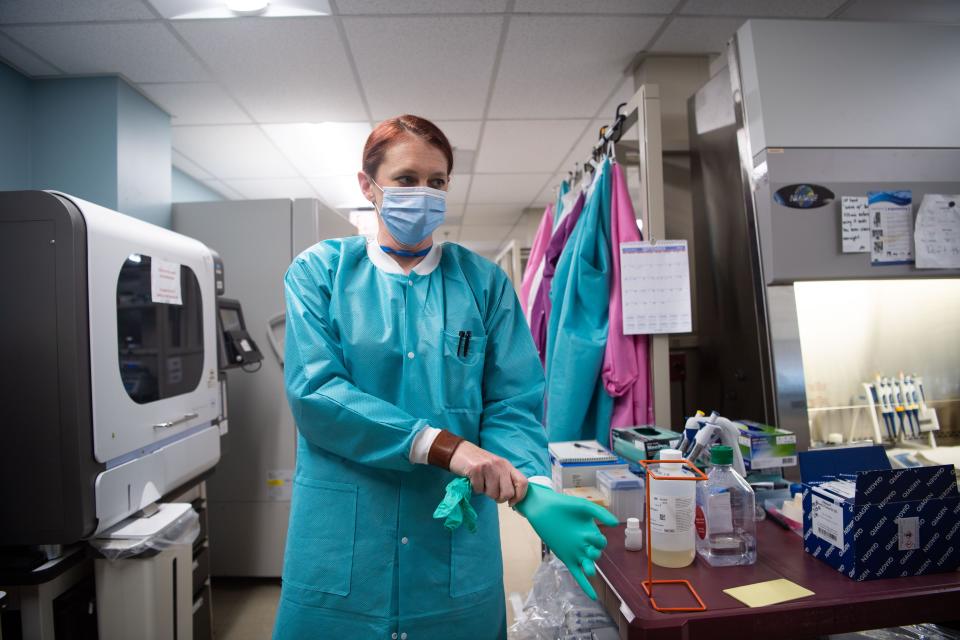 Karen Maynard, a laboratory scientist at the Tennessee public health lab, puts on rubber gloves in preparation to begin the COVID-19 genome sequencing process in Nashville, Tenn., Tuesday, Sept. 14, 2021.