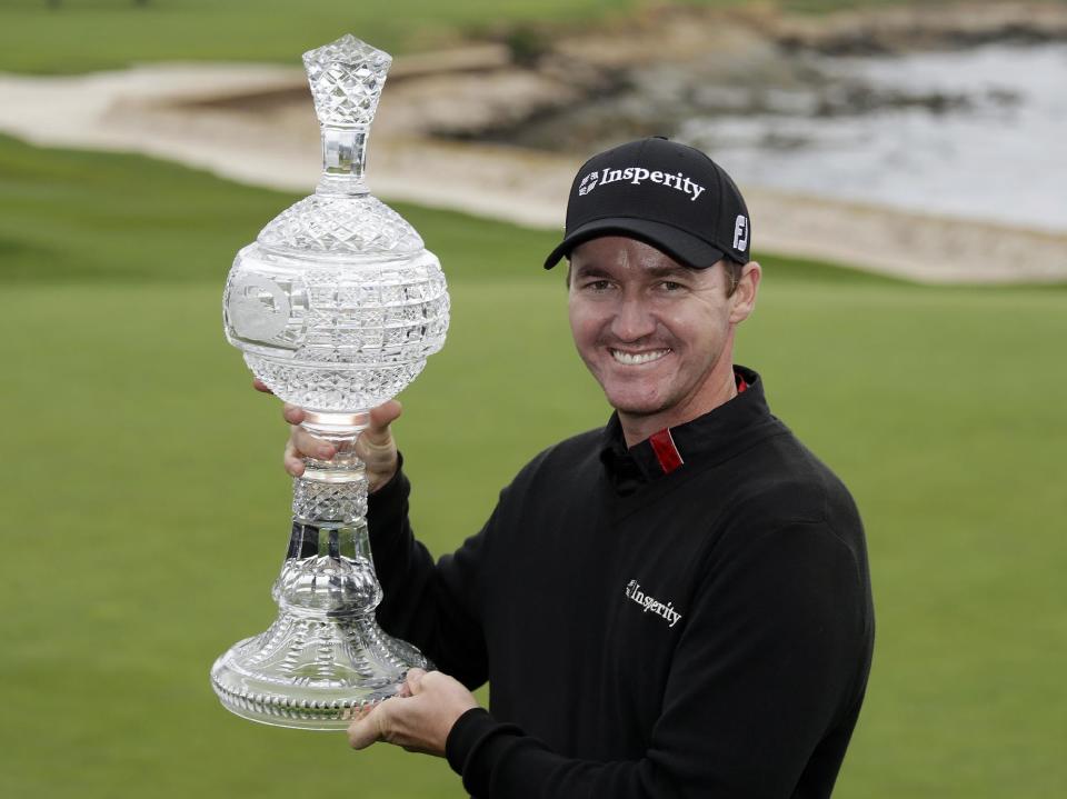 Jimmy Walker poses with his trophy on the 18th green of the Pebble Beach Golf Links after winning the AT&T Pebble Beach Pro-Am golf tournament Sunday, Feb. 9, 2014, in Pebble Beach, Calif. Walker shot a 2-over-par 74 to finish at total 11-under-par. (AP Photo/Eric Risberg)