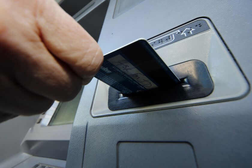 FILE - In this Saturday, Jan. 5, 2013 file photo, a person inserts a debit card into an ATM in Pittsburgh. Whether you're a customer who is coming to or leaving a bank, mergers and acquisitions are a good time to evaluate your banking needs. (AP Photo/Gene J. Puskar, File)