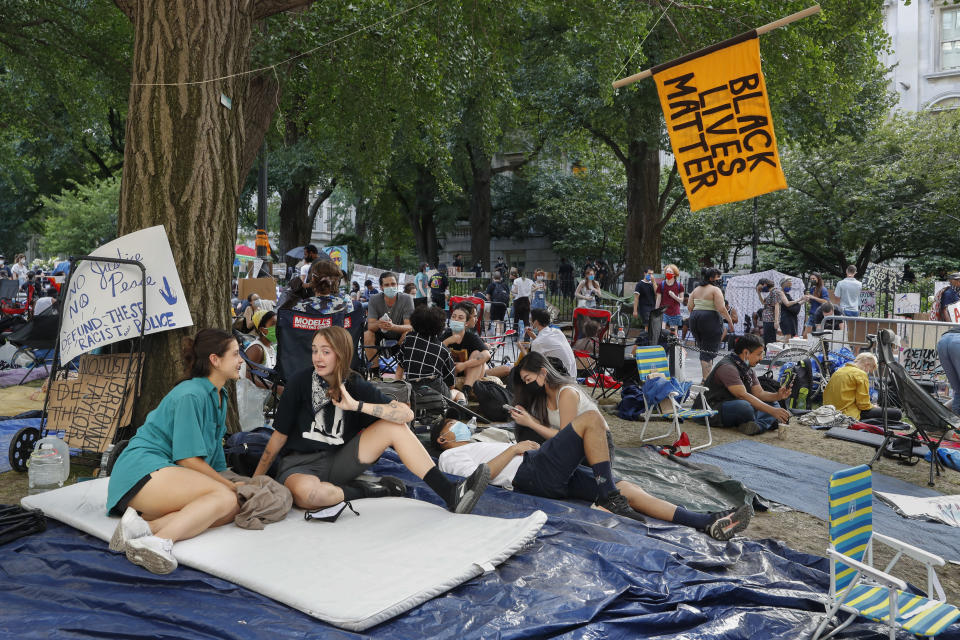 Protesters gather beneath a Black Lives Matter sign at an encampment outside City Hall, Friday, June 26, 2020, in New York. (AP Photo/John Minchillo)