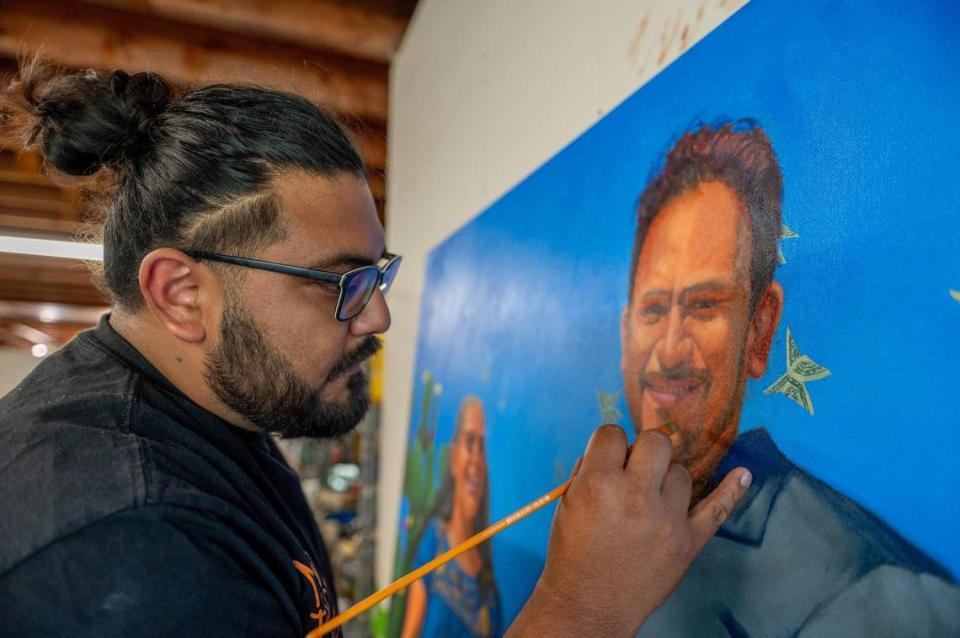 Artist Isaac Tapia works on his painting called “Pasado y Presente” at his Kansas City art studio. Tapia was preparing the painting of his parents to be part of a show featuring the works of Latino artists at The Nelson-Atkins Museum. The exhibit called “A layered Presence / Una presencia estratificada” started in October and shows through most of 2024. Emily Curiel/ecuriel@kcstar.com