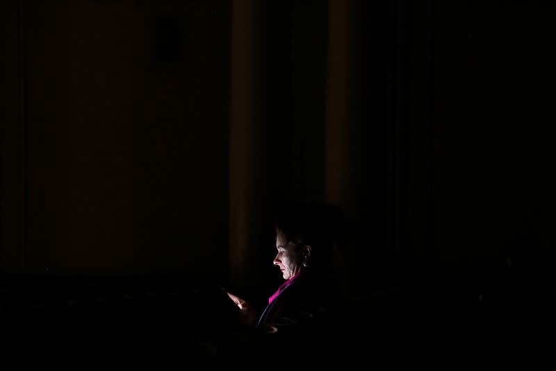 A woman uses a mobile phone to illuminate herself while attending the Kyiv Chamber Orchestra performance during power outages at the The National Philharmonic of Ukraine in Kyiv, Ukraine