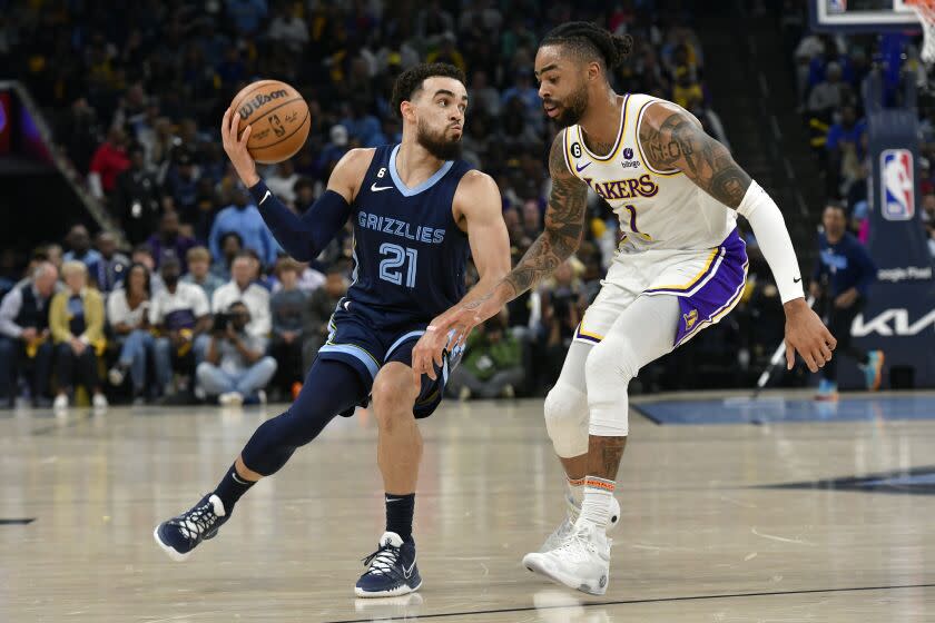 Memphis Grizzlies guard Tyus Jones (21) handles the ball against Los Angeles Lakers guard D'Angelo Russell (1) during Game 1 of a first-round NBA basketball playoff series, Sunday, April 16, 2023, in Memphis, Tenn. (AP Photo/Brandon Dill)