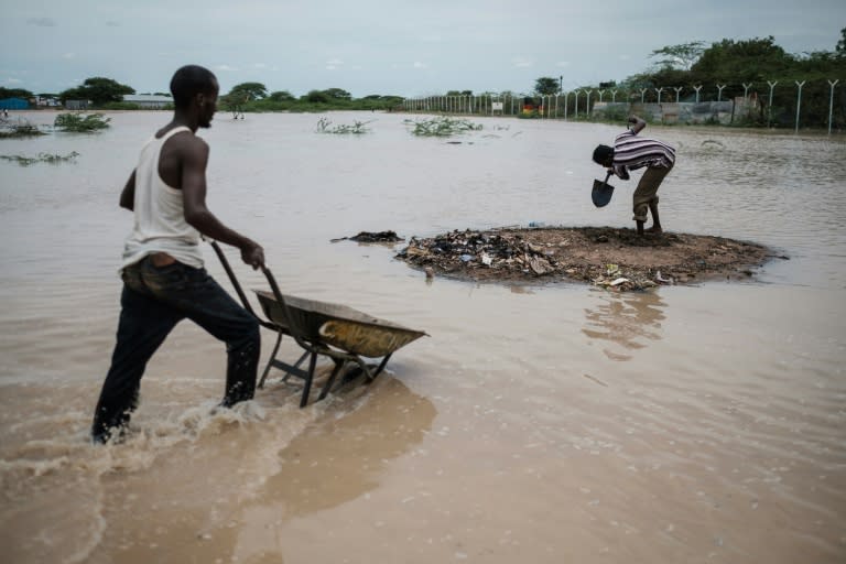 Men dig at a hump of raised earth as part of a bid to fill sandbags meant to protect shelters from rising waters