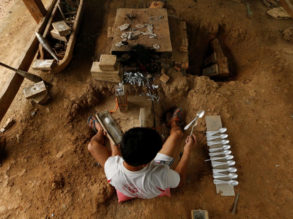 A man makes spoons by melting the bombs dropped by the U.S. Air Force planes during the Vietnam War, in the village of Ban Napia in Xieng Khouang province, Laos