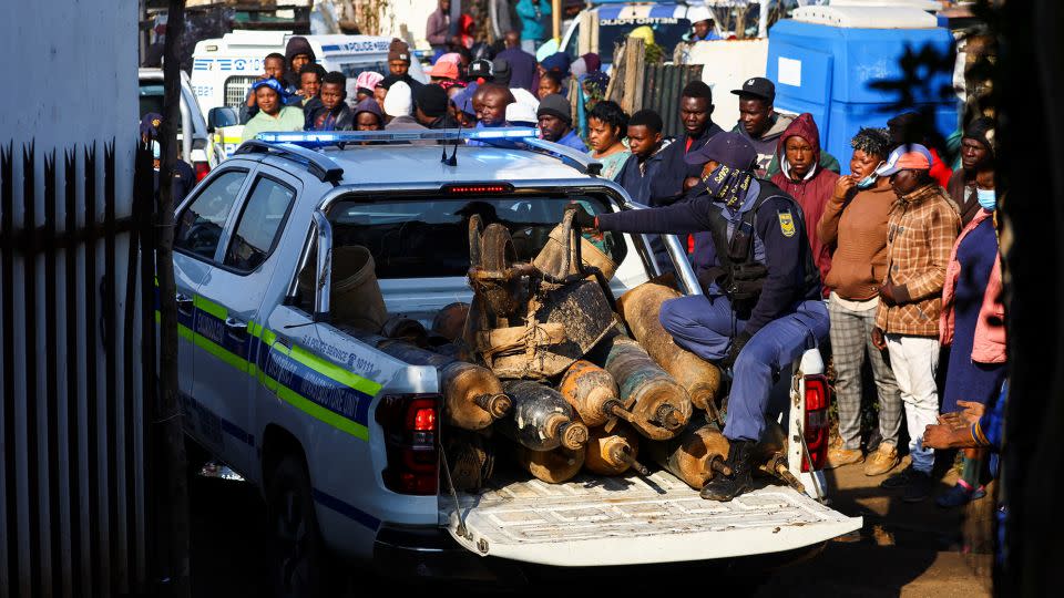 A police officer sits in the back of a police vehicle loaded with illegal mining equipment, after investigating the scene of a suspected gas leak thought to be linked to illegal mining, in the Angelo shack settlement, near Boksburg, east of Johannesburg, South Africa July 6, 2023. - Siphiwe Sibeko/Reuters