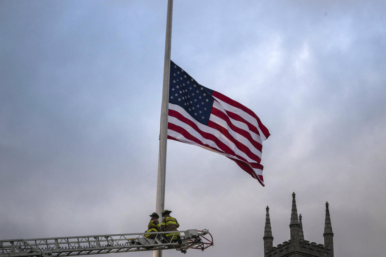 Firefighters lower the American flag to half-staff on Main Street in Newtown, Conn.