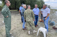 In this image released by the Romanian Defense Ministry, Defense Minister Angel Tilvar, third left, visits a Danube Delta village close to the Ukrainian border, Wednesday, Sept. 6, 2023. Romania's defense minister said Wednesday that pieces apparently of a drone from Russia's recent attacks on Ukraine's port on the Danube River have been found on the territory of his country. Romania is a NATO member. (Romanian Defense Ministry via AP)