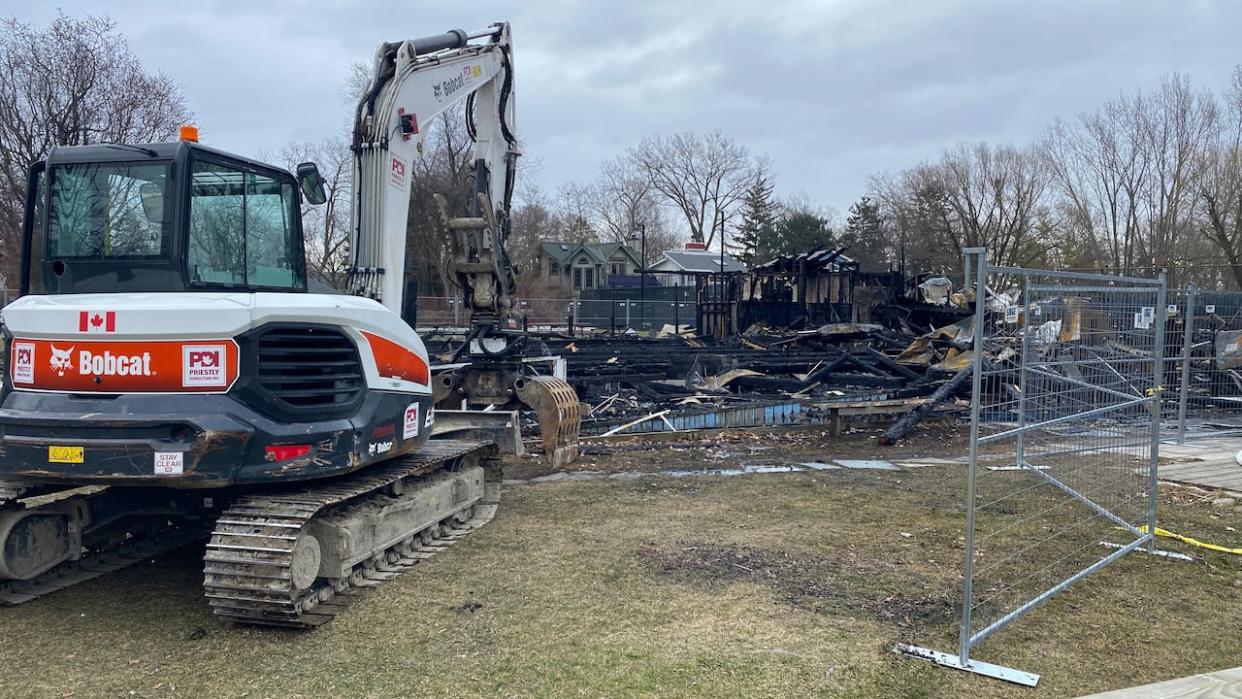 Heavy machinery was brought in Monday to assist firefighters as they combed through the rubble of the former Ward's Island Association Clubhouse.  (Paul Smith/CBC - image credit)