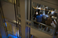 People wearing face masks to protect against the coronavirus ride an elevator at a shopping mall in Beijing, Friday, Aug. 14, 2020. China's factory output rose just under 5% last month from a year earlier while retail sales fell slightly, suggesting the country's recovery from the coronavirus pandemic remains muted. (AP Photo/Mark Schiefelbein)