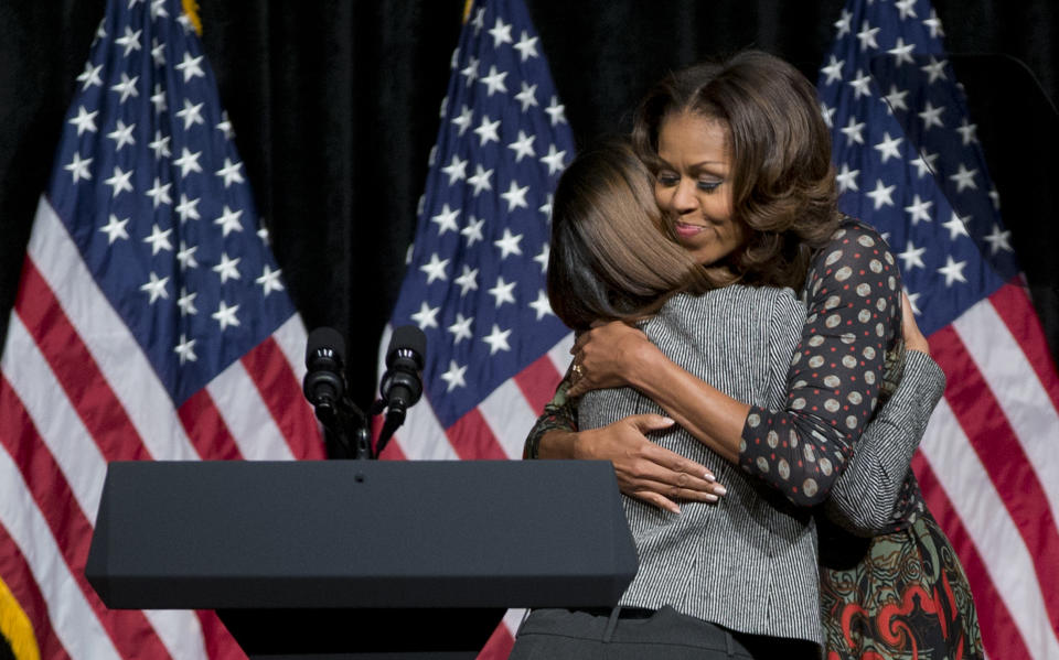 First lady Michelle Obama hugs Bell Multicultural High School alumni Menbere Assefa as she arrives to speak at school in Washington, Tuesday, Nov. 12, 2013. Mrs. Obama spoke to students about committing to education to create a better future for themselves and their country. Assefa introduced the first lady. (AP Photo/Carolyn Kaster)