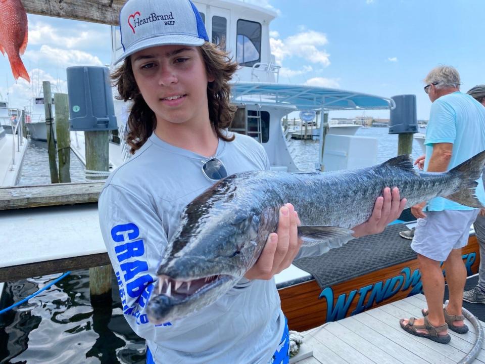 Skyler Gordon of Texas shows off a barracuda he caught on Friday while fishing with Capt. Tommy Carter on the  Blue Runner II.