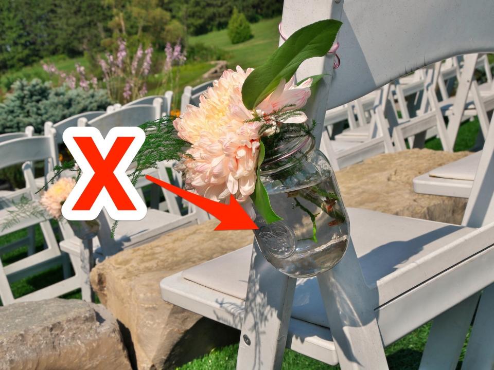 A mason jar attached to a chair with flowers in it. A red arrow and a red x point to the jar.
