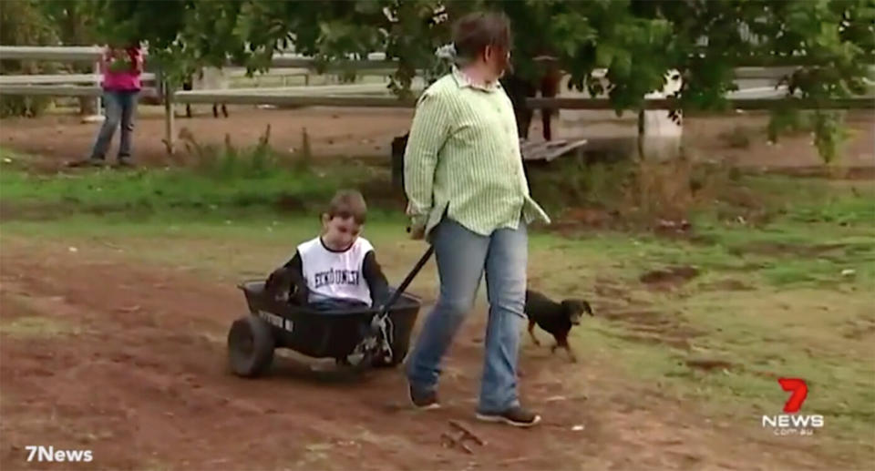 Angus's old wheelchair has become too difficult and unsafe to push around on the Darling Downs property, so he’s been getting around in a wheelbarrow. Source: 7NEWS