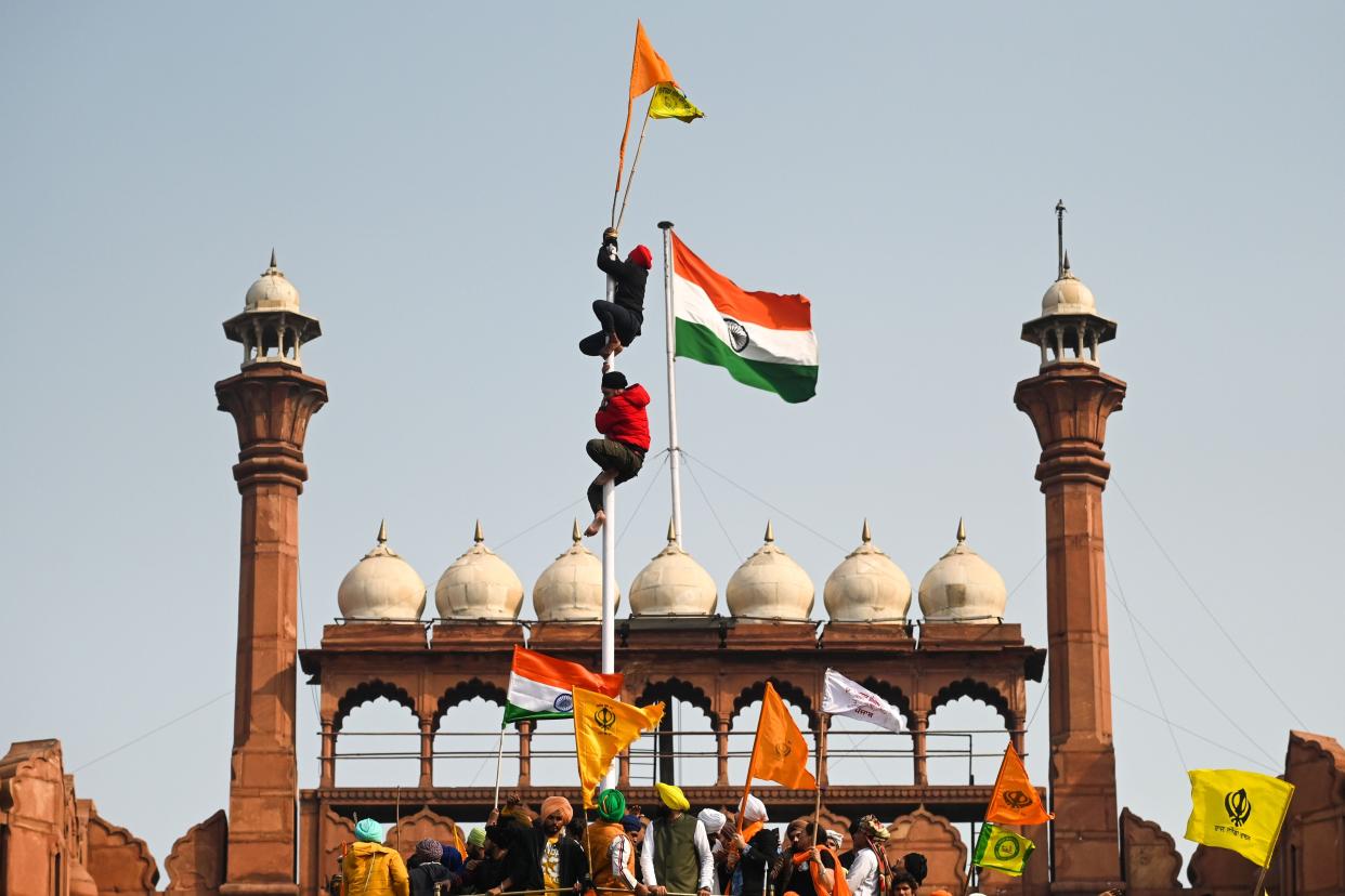 <p>Protesters climb a flagpole at the ramparts of the Red Fort as farmers continue to demonstrate against the central government’s recent agricultural reforms in Delhi</p> (AFP)