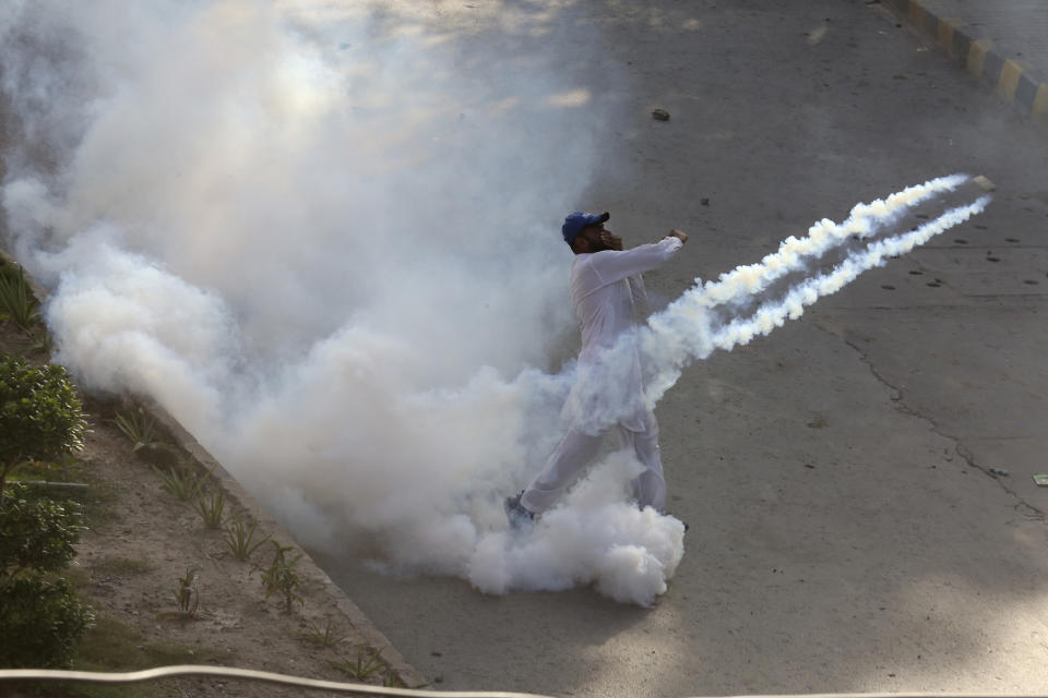 A supporter of Pakistan's former Prime Minister Imran Khan hurls back a tear gas shell toward police as he with others protesting against the arrest of their leader, in Peshawar, Pakistan, Tuesday, May 9, 2023. Khan was arrested and dragged from court as he appeared there to face charges in multiple graft cases, a dramatic escalation of political tensions that sparked violent demonstrations by his supporters in major cities. (AP Photo/Muhammad Sajjad)
