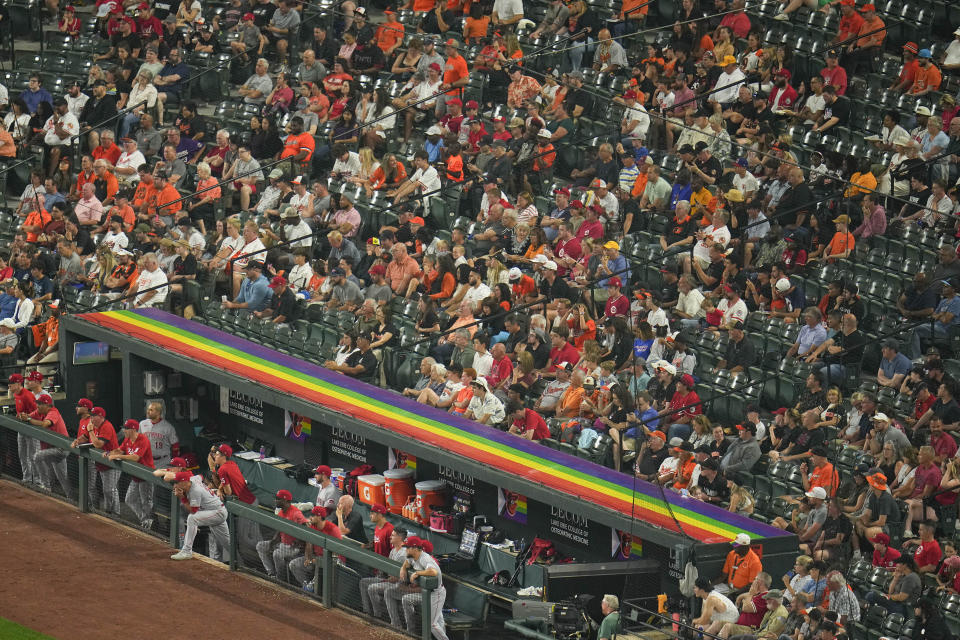 The Cincinnati Reds dugout is decorated in a flag in honor of Pride Night in the sixth inning of a baseball game between the Baltimore Orioles and the Cincinnati Reds, Wednesday, June 28, 2023, in Baltimore. (AP Photo/Julio Cortez)