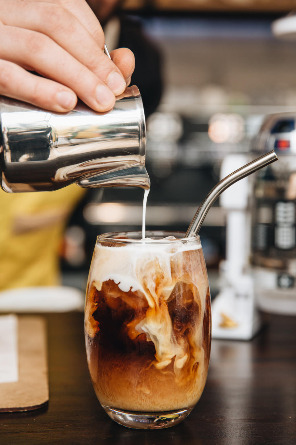 Pouring milk into iced coffee.