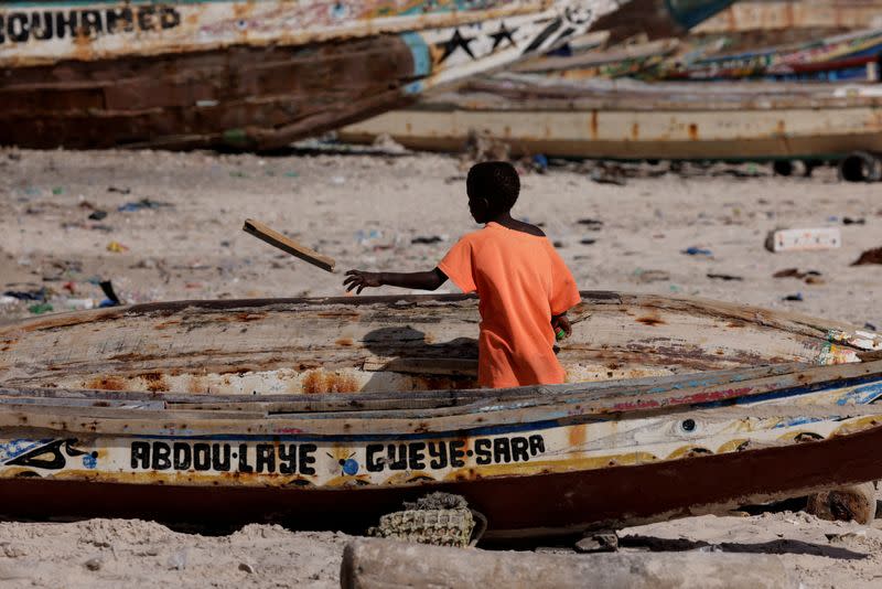 FILE PHOTO: A boy cleans a Senegalese fishing pirogue on the beach in Bargny on the outskirts of Dakar