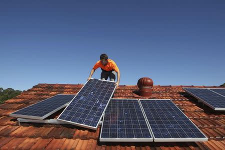 Solar system installer Thomas Bywater adjusts new solar panels on the roof of a house in Sydney in this August 19, 2009 file photo. REUTERS/Tim Wimborne/Files