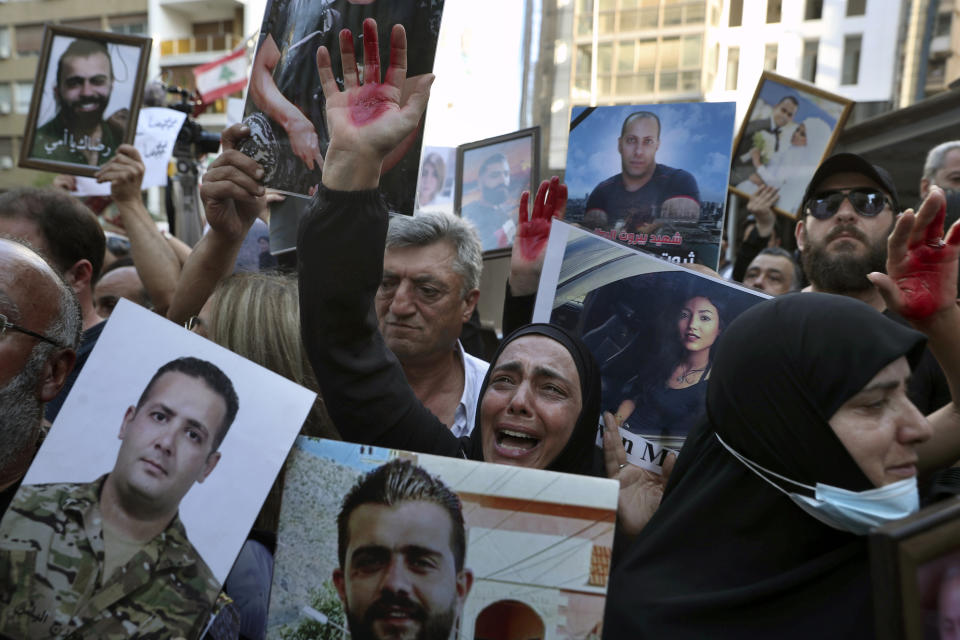 A mother whose son was killed during last year's massive blast at Beirut's seaport, weeps as she raises her hand painted red to represent blood, outside the home of caretaker Interior Minister Mohamed Fehmi, in Beirut, Lebanon, Tuesday, July 13, 2021. Family members are angry with Fehmi because he rejected a request by the judge investigating the explosion to question Maj. Gen. Abbas Ibrahim, who is one of Lebanon's most prominent generals and heads of the General Security Directorate. (AP Photo/Bilal Hussein)