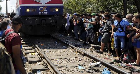 Migrants sitting along a railway track on the Greek side of the border move away as a train approaches the Greek-Macedonian border, near Gevgelija August 24, 2015. REUTERS/Ognen Teofilovski